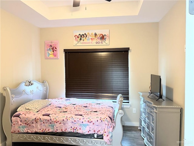 bedroom with hardwood / wood-style floors, a raised ceiling, and ceiling fan