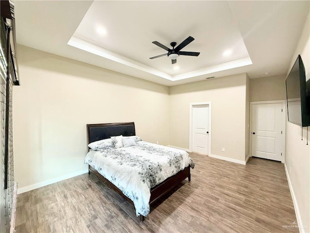 bedroom featuring hardwood / wood-style floors, ceiling fan, and a tray ceiling