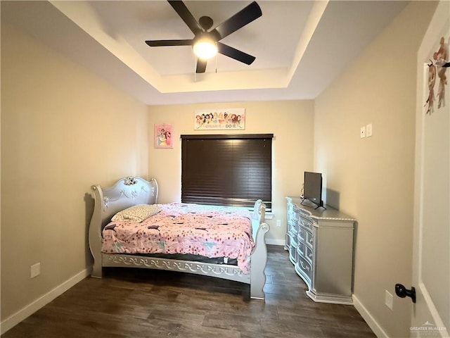 bedroom with a raised ceiling, ceiling fan, and dark hardwood / wood-style flooring