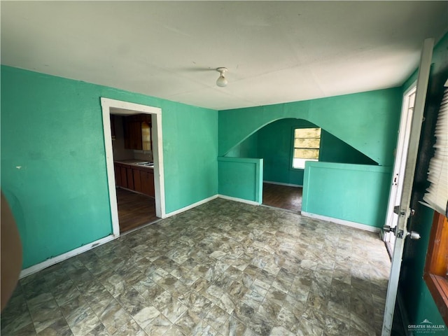 210 N Palmas St, Weslaco, TX 78596 - unfurnished room with arched walkways, baseboards, and stone finish floors