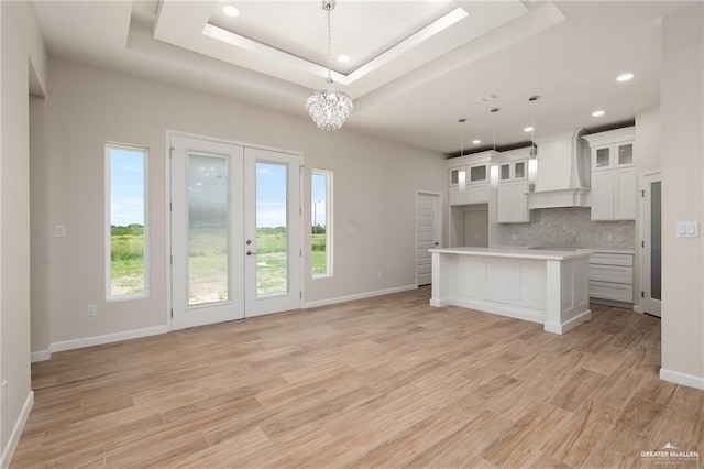 kitchen featuring tasteful backsplash, a center island, custom exhaust hood, a raised ceiling, and hanging light fixtures