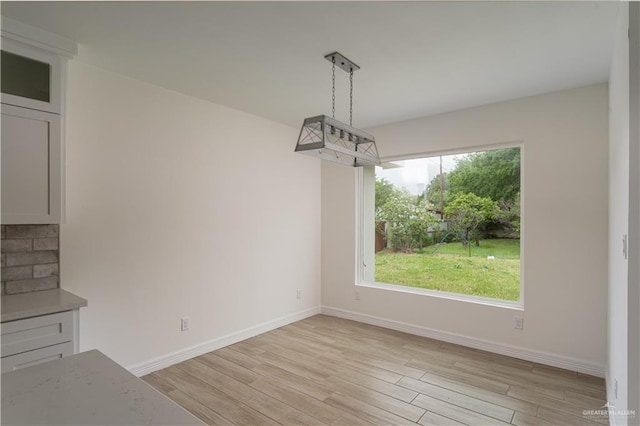 unfurnished dining area with baseboards and light wood-style flooring