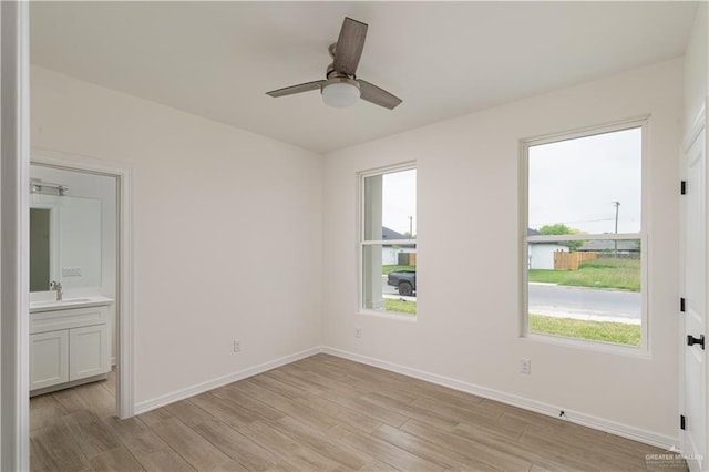 unfurnished bedroom featuring multiple windows, a sink, and light wood-style floors