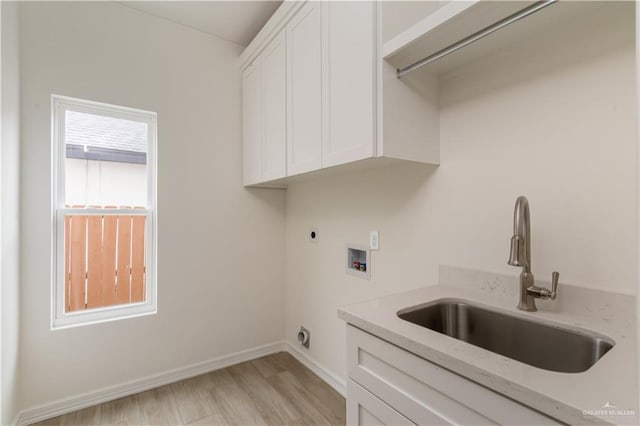 clothes washing area with hookup for an electric dryer, cabinet space, a sink, hookup for a washing machine, and light wood-style floors