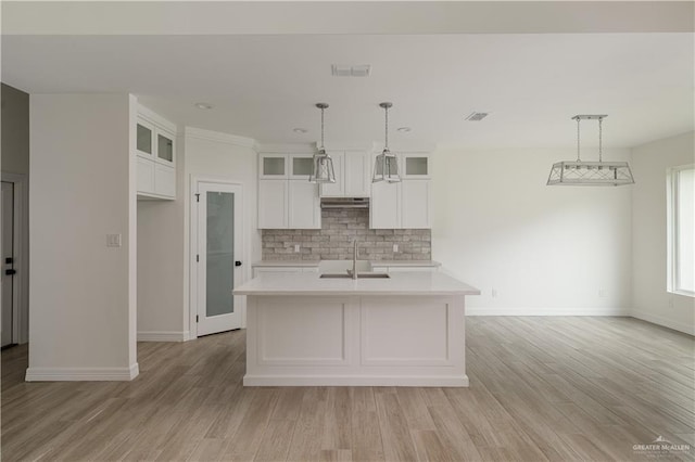 kitchen with white cabinets, a sink, light countertops, baseboards, and decorative backsplash