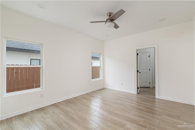spare room featuring light wood-style floors, baseboards, and ceiling fan