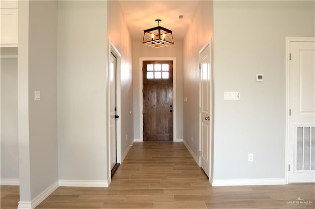 doorway with light hardwood / wood-style floors and a notable chandelier