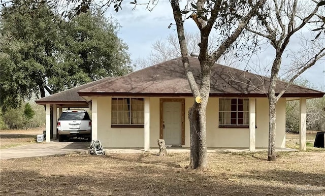 ranch-style home with stucco siding, a shingled roof, concrete driveway, and an attached carport