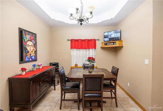 tiled dining space featuring a raised ceiling and an inviting chandelier