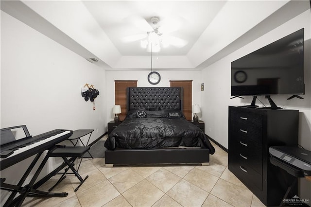 bedroom with ceiling fan, a raised ceiling, and light tile patterned floors