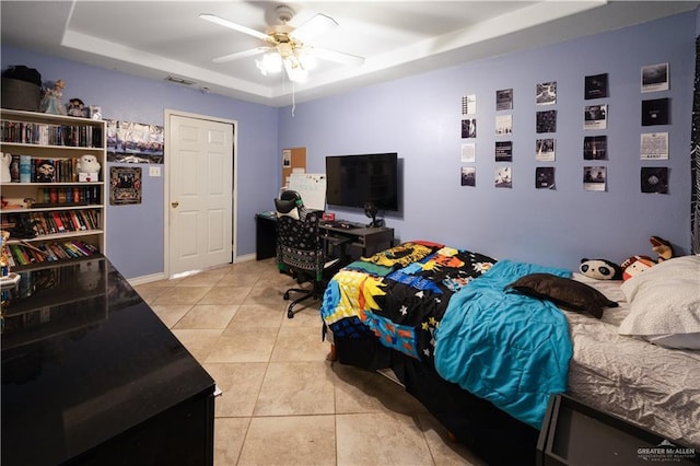 tiled bedroom featuring ceiling fan and a raised ceiling