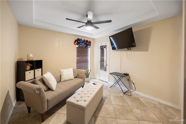 tiled living room featuring a raised ceiling and ceiling fan