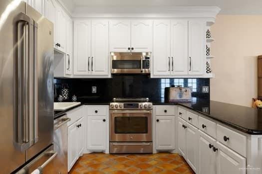 kitchen featuring backsplash, kitchen peninsula, white cabinetry, and appliances with stainless steel finishes