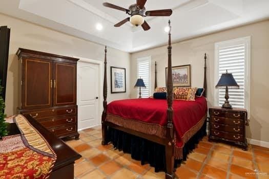 bedroom featuring a raised ceiling, ceiling fan, and light tile patterned floors