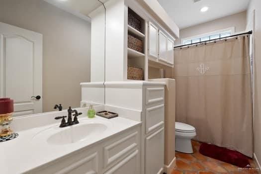 bathroom featuring toilet, walk in shower, and sink