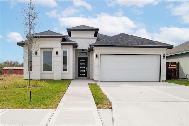 prairie-style home featuring driveway, a front lawn, roof with shingles, and an attached garage