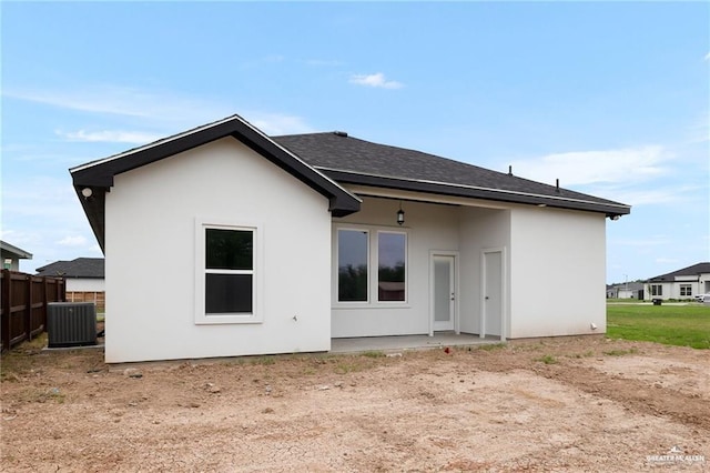 back of property featuring a shingled roof, cooling unit, fence, and stucco siding