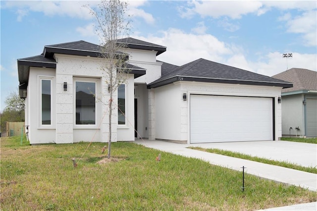 prairie-style home featuring driveway, a shingled roof, an attached garage, a front yard, and stucco siding