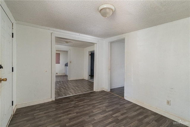 empty room with a textured ceiling, baseboards, and wood finished floors