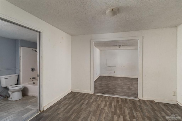 interior space with a textured ceiling, baseboards, and dark wood-style flooring