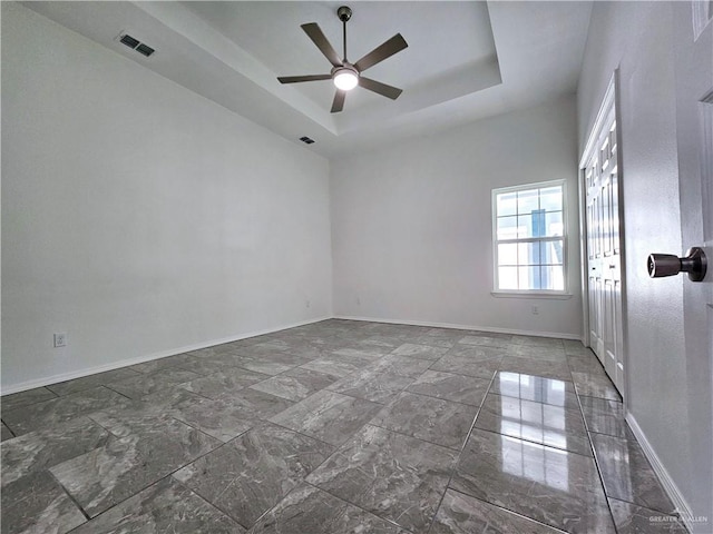 unfurnished room featuring ceiling fan and a tray ceiling