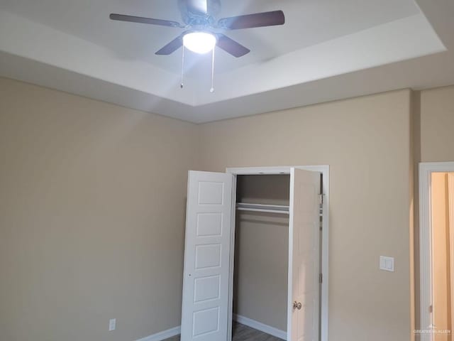 unfurnished bedroom with ceiling fan and a closet