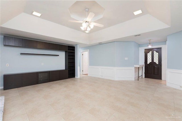 409 Kiwi Ave, Mcallen, TX 78504 - unfurnished living room featuring a tray ceiling, a decorative wall, a ceiling fan, built in shelves, and tile patterned flooring