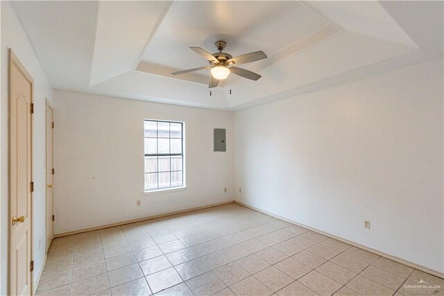 tiled spare room featuring ceiling fan, a raised ceiling, and electric panel