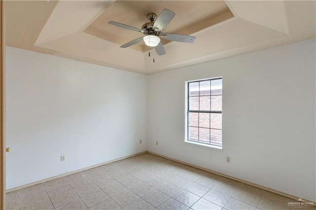 tiled empty room with a raised ceiling and ceiling fan