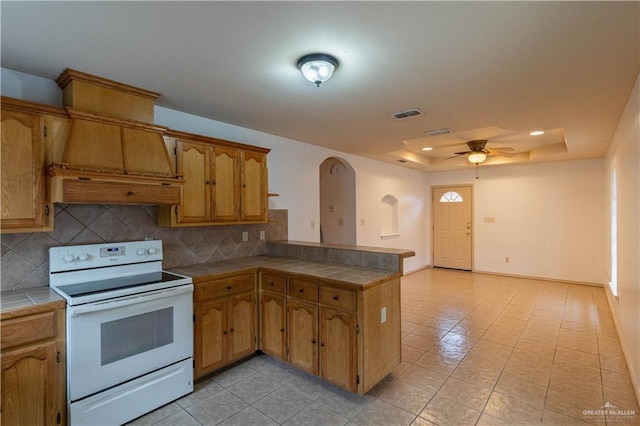 kitchen with backsplash, white range with electric stovetop, tile counters, and ceiling fan