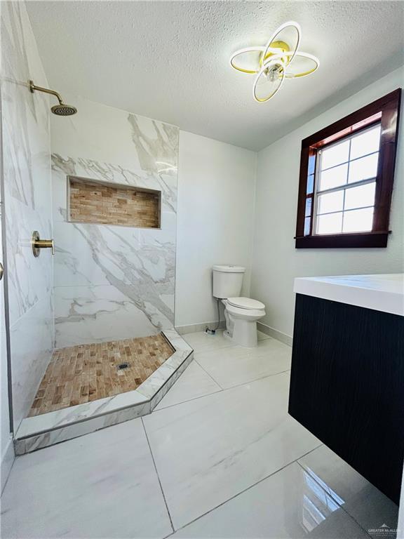 bathroom featuring a tile shower, a textured ceiling, and toilet