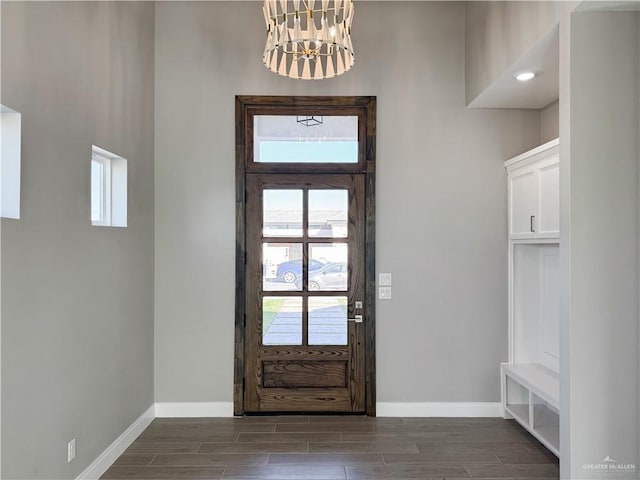 entrance foyer featuring an inviting chandelier, baseboards, and wood tiled floor