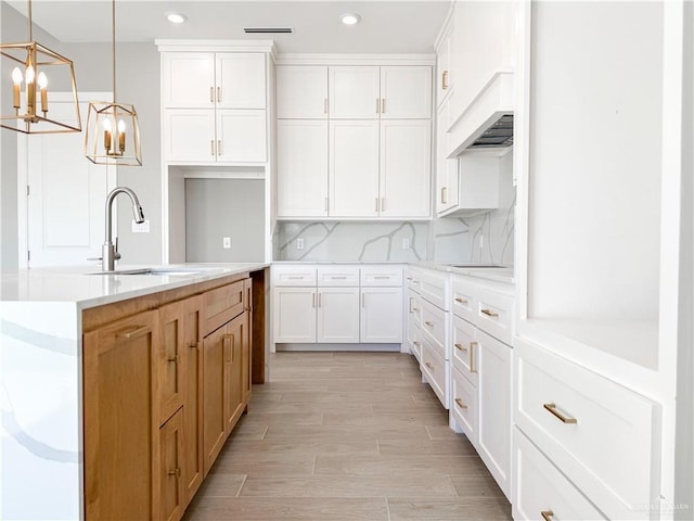 kitchen featuring a sink, light wood-type flooring, tasteful backsplash, and white cabinets