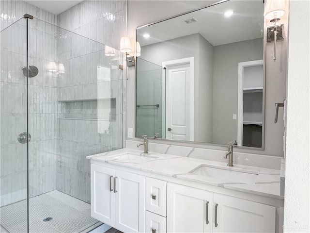 bathroom with a sink, visible vents, double vanity, and a shower stall