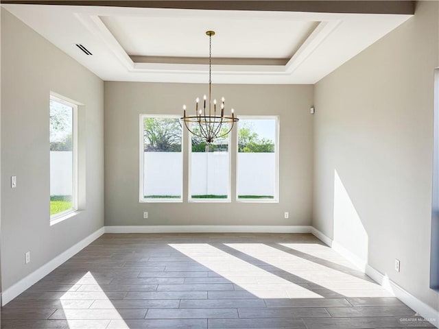 empty room featuring visible vents, baseboards, a tray ceiling, and wood finished floors