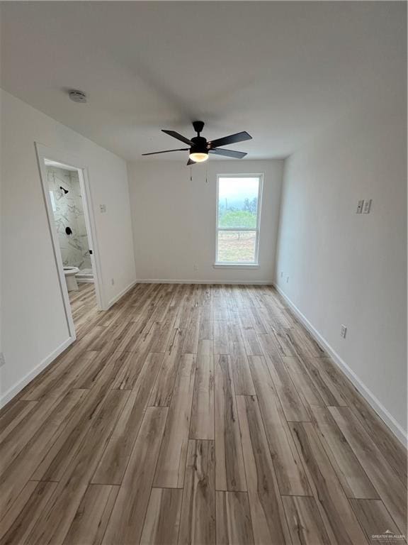 spare room with ceiling fan, light wood-style flooring, and baseboards