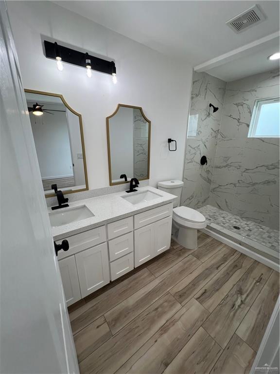 full bathroom with visible vents, a sink, toilet, and wood finished floors