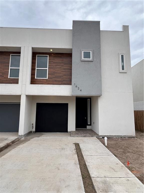 view of front facade with a garage, fence, concrete driveway, and stucco siding