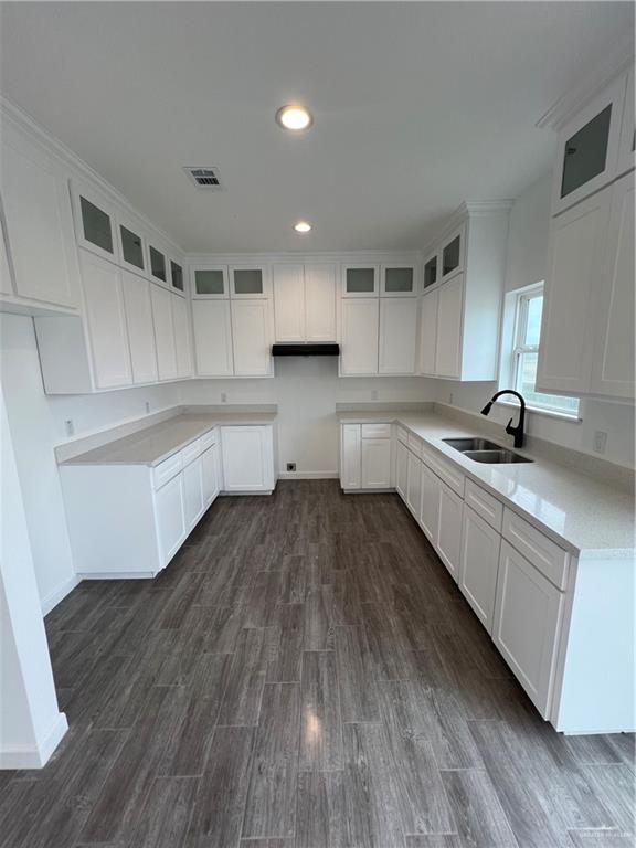 kitchen with white cabinets, glass insert cabinets, dark wood-type flooring, and a sink