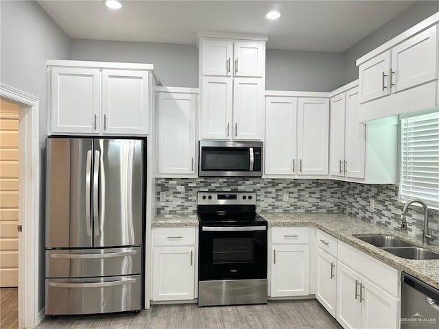 3708 Climax Dr, Edinburg, TX 78542 - kitchen with appliances with stainless steel finishes, white cabinetry, light wood-type flooring, decorative backsplash, and light stone countertops