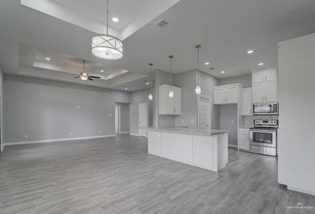 3708 Climax Dr, Edinburg, TX 78542 - kitchen featuring stainless steel appliances, a raised ceiling, open floor plan, white cabinetry, and backsplash