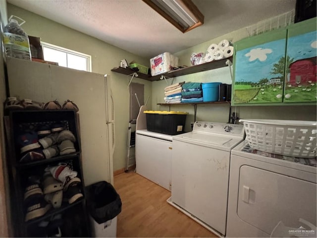 clothes washing area with separate washer and dryer, a textured ceiling, and light wood-type flooring