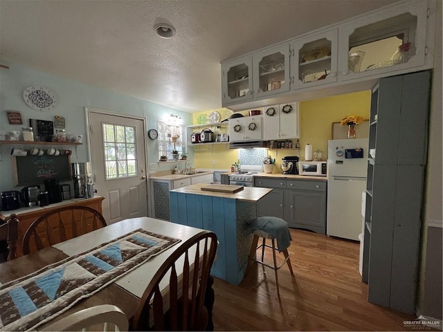 kitchen featuring white appliances, white cabinets, sink, hardwood / wood-style flooring, and a textured ceiling