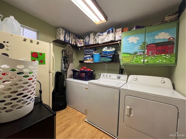 laundry room with washing machine and clothes dryer and light wood-type flooring