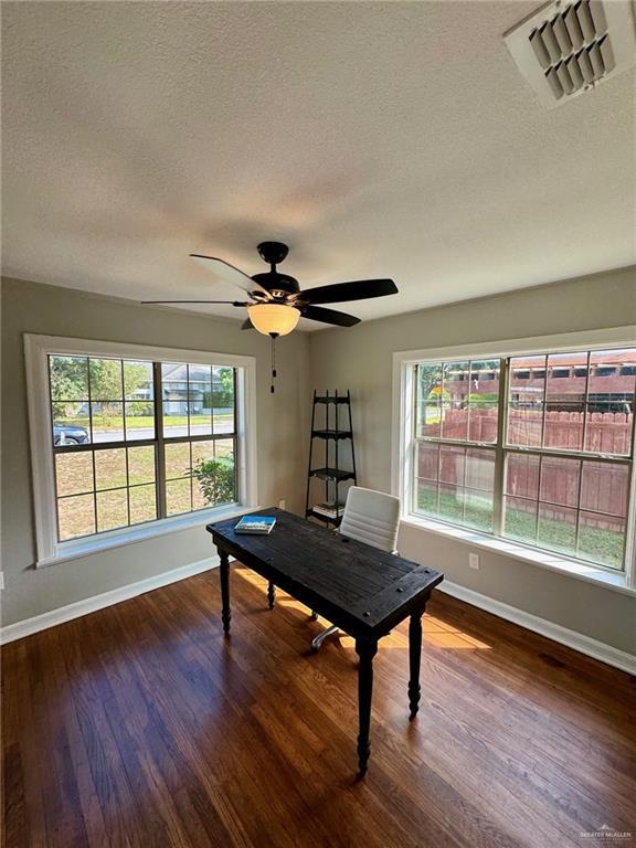 playroom featuring a wealth of natural light, dark wood-type flooring, and a textured ceiling