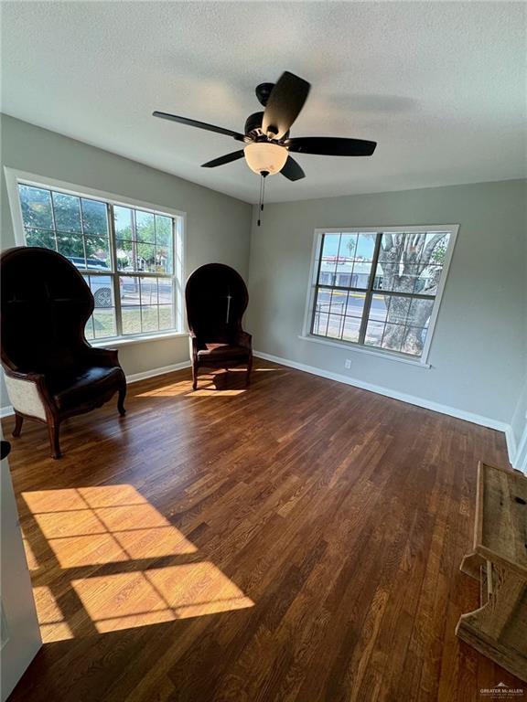 living area with ceiling fan, hardwood / wood-style floors, and a textured ceiling