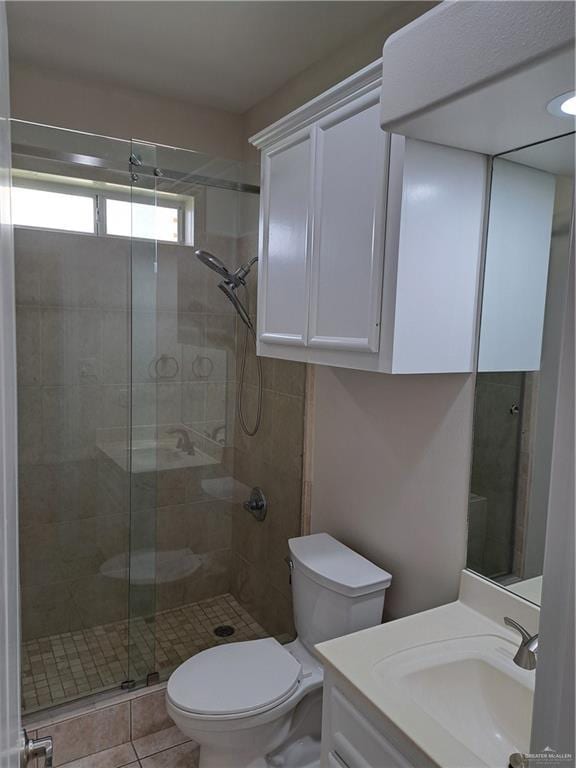 bathroom with tile patterned flooring, vanity, a shower with door, and toilet