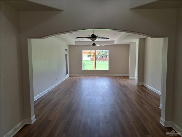 spare room featuring a raised ceiling, ceiling fan, and dark hardwood / wood-style flooring