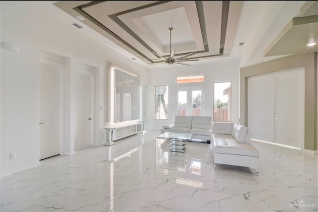 unfurnished living room featuring a raised ceiling, french doors, and ceiling fan