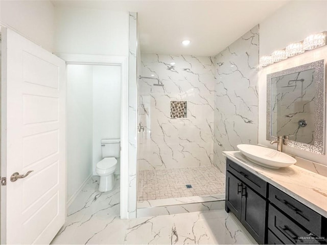 bathroom with toilet, tiled shower, and vanity